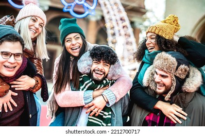 Happy International Friends Walking At Winter Travel Location On Piggy Back Move - Everyday Life Style Concept With Happy Guys And Girls Having Fun Together Outside - Bright Contrast Filter