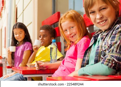 Happy international kids sit in outside cafe