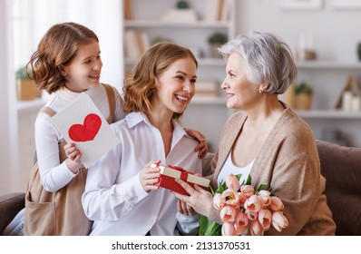 Happy International Women's Day. Smiling Multi Generational Family Grandmother, Mother And Daughter With Flowers  Cheerfully Celebrate The Spring Holiday Mother's Day At Home