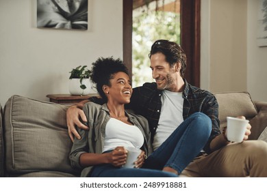 Happy, interracial couple and drinking coffee in home, talking or bonding together for love in living room. Tea cup, man and funny woman in conversation for joke, story or laughing at comedy on sofa - Powered by Shutterstock