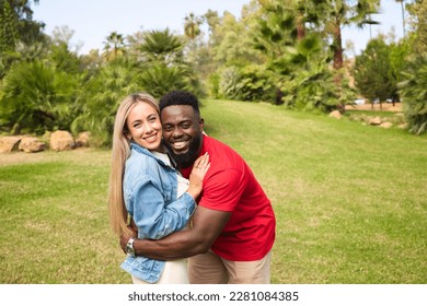 Happy interracial couple hugging in park looking at camera for photo. They are happy and excited. - Shutterstock ID 2281084385