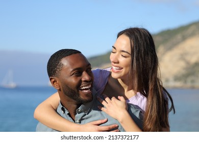 Happy interracial couple laughing on the beach on summer vacation - Powered by Shutterstock