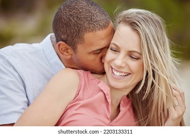 Happy Interracial Couple, Love And Smile For Relationship Together In Nature Happiness And Outdoors. Man And Woman Smiling In Joyful Marriage, Neck Kiss And Bonding Time Outside On Holiday Vacation