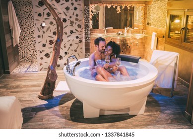 Happy interracial couple relaxed in the jacuzzi enjoying their self and drinking wine 