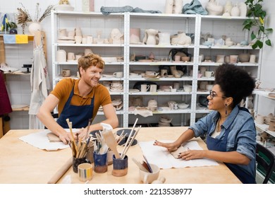 happy interracial couple smiling while shaping clay during pottery class - Powered by Shutterstock