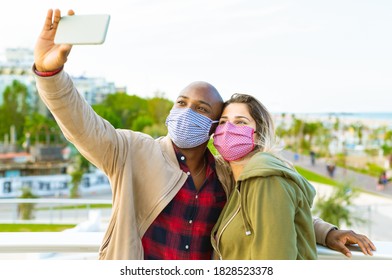 happy interracial couple wearing face mask taking a selfie on the seaside in a autumn holidays . concept about the new normality lifestyle on vacation and on a daily bases - Powered by Shutterstock