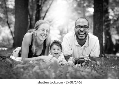 Happy Interracial Family Is Enjoying A Day In The Park. Little Baby Boy. Black And White B&W Picture.