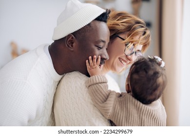 Happy interracial family has fun and plays with their baby daughter. Concept of interracial family and unity between different human races. - Shutterstock ID 2234299679