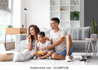 Happy Interracial Family With Laptop Eating Chips At Home