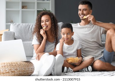 Happy Interracial Family With Laptop Eating Chips At Home