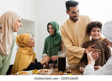 Happy interracial muslim family talking near food at home