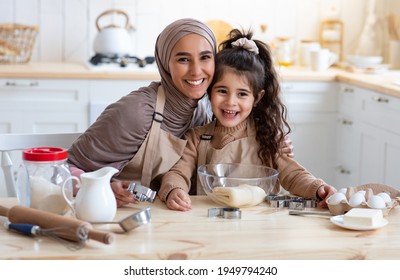 Happy Islamic Family Mother And Little Daughter Baking In Together In Kitchen, Cute Preschool Girl And Her Muslim Mom In Hijab Preparing Homemade Cookies, Having Fun At Home, Free Space - Powered by Shutterstock