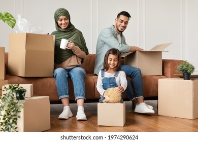 Happy Islamic Family Packing For A House Move, Sitting With Open Boxes Indoors In Living Room. Young People Housing, Real Estate Purchase And Apartment Rent, Relocation Concept. Free Place