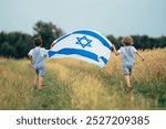 Happy israeli jewish little boys runs with Israel national flag. Independence Day. Patriotism. Patriot kids, friends on open area field. Symbol of democracy, independence, future. High quality photo