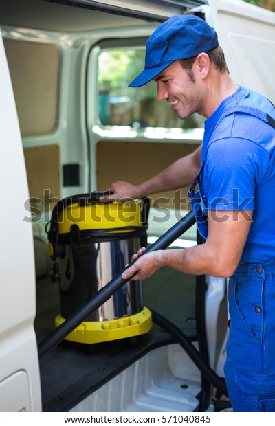 Happy\
janitor cleaning the car with vacuum\
cleaner