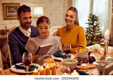 Happy Jewish Family Reading Tanakh While Having Meal At Dining Table On Hanukkah.