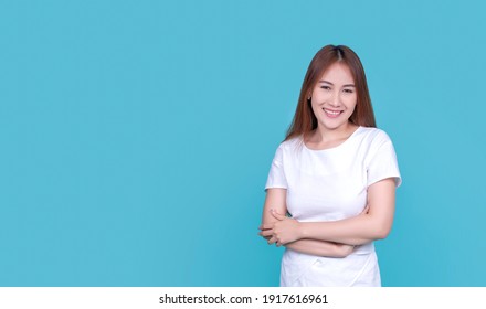 Happy Joyful Excited Smiling Confident Asian Woman Arms Crossed Strong Independent, Wearing Blank White Clothing Standing, Copyspace Banner Isolated Blue Background Advertisement Marketing Concept