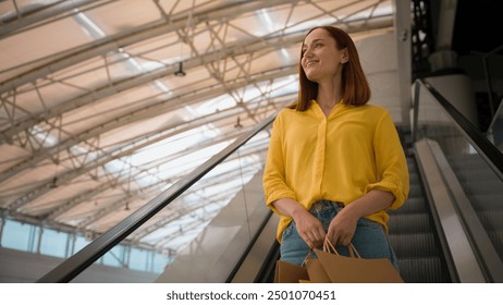 Happy joyful glad Caucasian female woman girl shopper client customer consumer tourist hold many paper bags enjoy shopping after flight riding escalator moving stairs inside shop mall airport terminal - Powered by Shutterstock