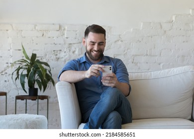 Happy joyful mobile phone user talking on video call, holding mobile phone, laughing, smiling at screen, sitting on couch at home, using online app on cell, watching social media content - Powered by Shutterstock