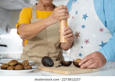 Happy joyful older husband and wife sharing cooking chores, making organic fresh salad together, cutting vegetables, talking, laughing. Old couple having fun in kitchen, preparing dinner - Powered by Shutterstock