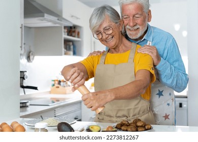 Happy joyful older husband and wife sharing cooking chores, making organic fresh salad together, cutting vegetables, talking, laughing. Old couple having fun in kitchen, preparing dinner - Powered by Shutterstock