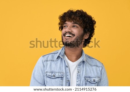 Happy joyful smiling young indian man looking aside up thinking of new good opportunities, dreaming, feeling inspired and proud standing isolated on yellow background. Portrait