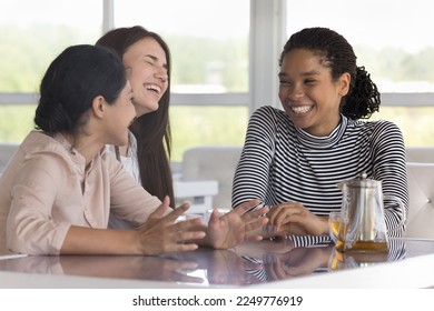 Happy joyful three diverse female friends having fun in cafe, talking, laughing, sitting at table, sharing news, gossip, drinking hot tea, enjoying meeting, leisure, break together - Powered by Shutterstock