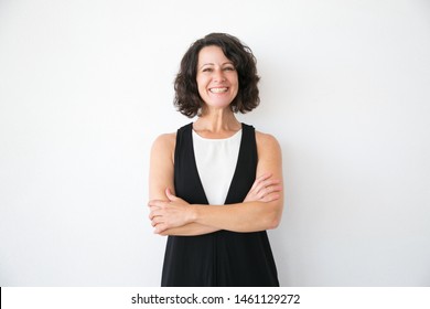 Happy Joyful Woman In Casual Posing Over White Studio Background. Portrait Of Cheerful Successful Middle Aged Business Lady With Arms Folded Smiling At Camera. Female Portrait Concept