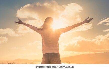 Happy joyful woman lifting her arms up to the sunny sky feeling joyful.