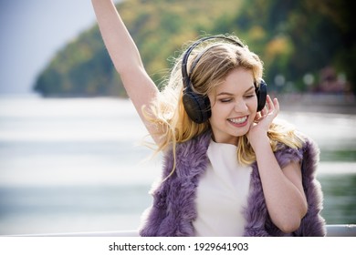 Happy Joyful Woman Listening To Music While Being Outdoor. Teenage Female Wearing Headphones Having Fun On A Walk.