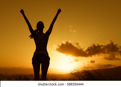 Happy joyful woman raising her arms up into the sky feeling happy and free. 
