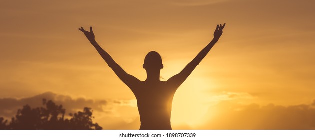 Happy Joyful Woman Silhouette With Arms Up To The Sunset Sky. 