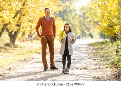 Happy Joyful Young Father With His Little Daughter. Father And Little Kid Having Fun Outdoors, Playing Together In Autumn Park. Dad With His Child Laughing And Enjoying Nature