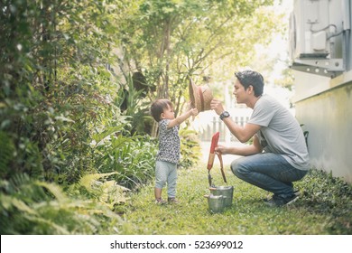 Happy Joyful Young Father With His Little Daughter. Father And Little Kid Having Fun Outdoors In Backyard Garden, Playing Together In Home Garden. Dad With His Child Laughing And Enjoying Nature.