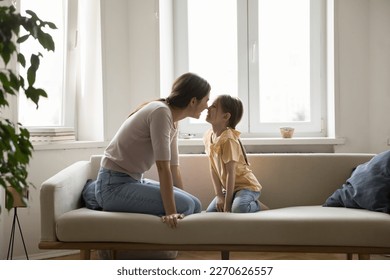 Happy joyful young mommy and cute playful kid enjoying family closeness, relationship, leisure, playing with nose touch, laughing, having fun. Cheerful mom enjoying motherhood, tenderness to daughter