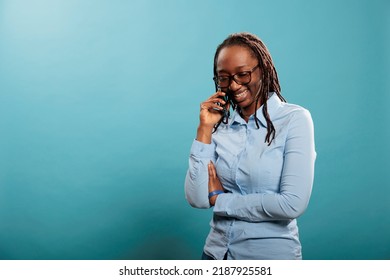 Happy Joyful Young Woman Smiling Heartily While Having A Phone Call Conversation On Blue Background. Cheerful Adult Person Talking With Friend On Touchscreen Cellphone Device.