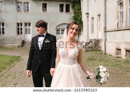 Happy just married couple in wedding clothes walking near the castle