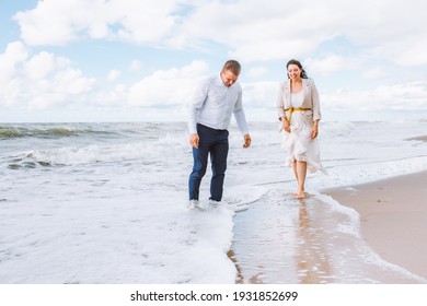Happy just married middle age couple walk at beach against blue sky with clouds and have fun at summer day. Togetherness, love, family