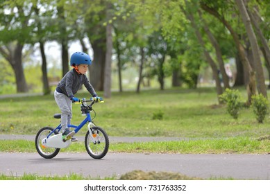 Happy Kid Boy Of 5 Years Having Fun In Spring Park With A Bicycle On Beautiful Fall Day. Active Child Wearing Bike Helmet