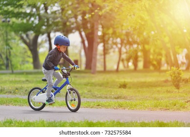 Happy Kid Boy Of 5 Years Having Fun In Spring Park With A Bicycle On Beautiful Fall Day. Active Child Wearing Bike Helmet