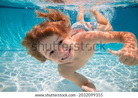Happy kid boy swim and dive underwater, kid with fun in pool under water. Active healthy lifestyle, water sport activity and swimming lessons on summer vacation with child.