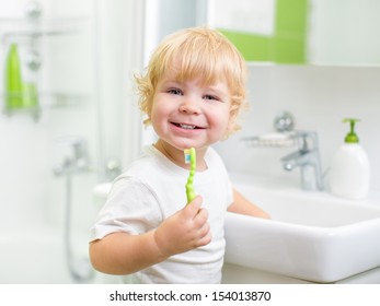 Happy Kid Or Child  Brushing Teeth In Bathroom. Dental Hygiene.