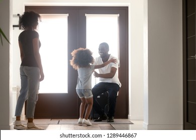 Happy Kid Daughter Excited To Meet African American Dad Arriving Coming Home After Business Trip With Suitcase, Father Hugging Child In House Hallway, Welcome Back Daddy Black Family Reunion Concept