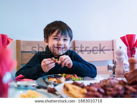 Happy kid eating sunday dinner at home, Child boy having Chirstmas lunch with family.
