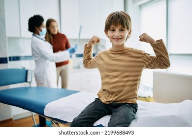 Happy Kid Flexing His Muscles After Medical Examination At Doctor's Office.