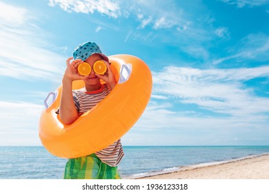 happy kid with fresh oranges and floatie on beach , concept of a healthy diet, vitamins, lifestyle