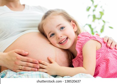 happy kid girl hugging pregnant mother's belly