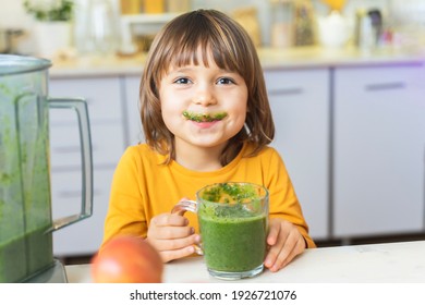 Happy Kid with glass cup of green smoothies in hands. Cute boy crazy drinks healthy dietary nutritious cocktail at home in the kitchen. Healthy lifestyle, raw food - Powered by Shutterstock