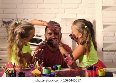 Happy Kid Having Fun. Body Art And Painting. Girls Drawing On Man Face Skin With Colorful Paints. Fathers Day And Family Concept. Daughters And Dad Smiling With Painted Hands. Creativity And