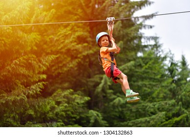 Happy kid with helmet and harness on zip line between trees - Powered by Shutterstock